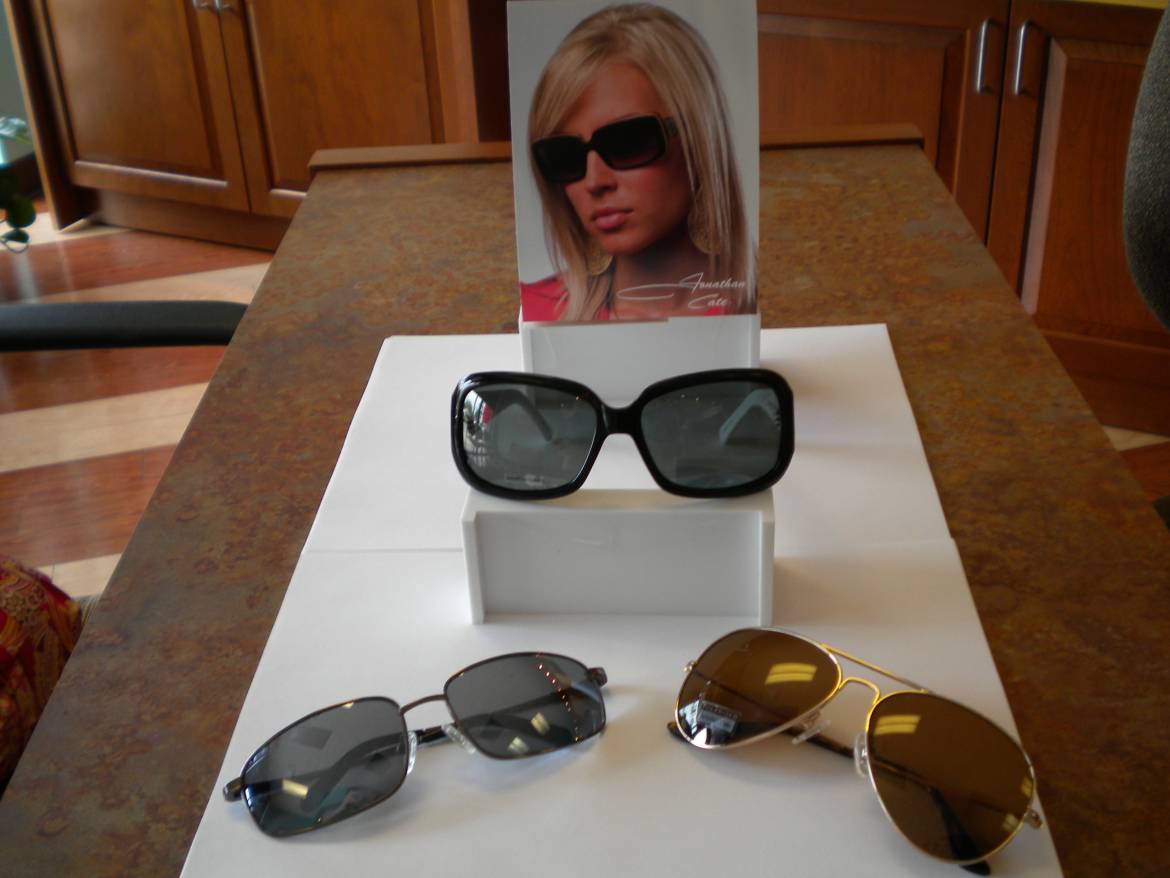 Three pairs of sunglasses sitting on a display stand.